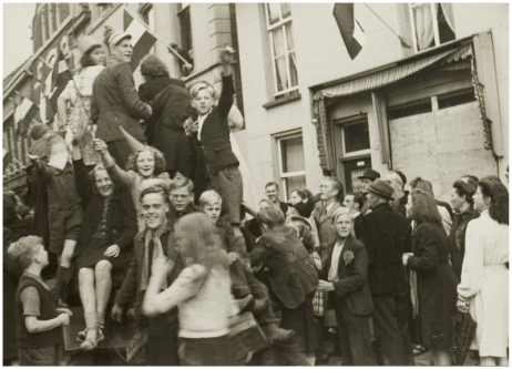 Uitgelaten Helmonders zien bij het beklimmen van een Britse tank op de kop van de Molenstraat. Fotograaf Atelier Prinses.